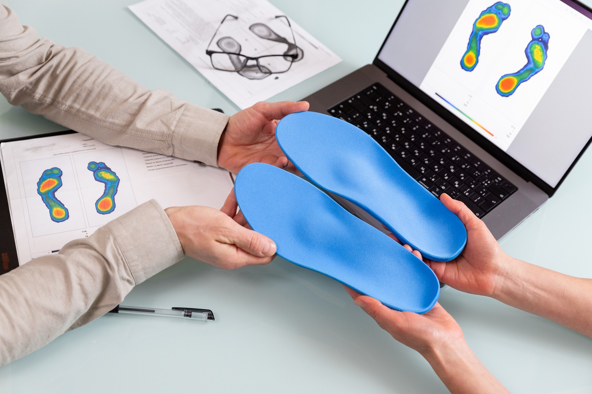 Female doctor orthopedist  presents new custom made insoles to a male patient in a clinic.